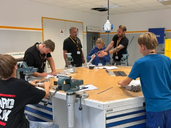Gruppe von Personen, die gemeinsam an einem Werkstatttisch mit Werkzeugen arbeiten