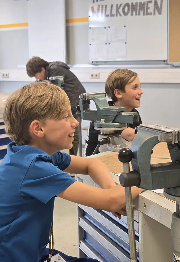 Zwei Jungen lächeln an einer Werkbank